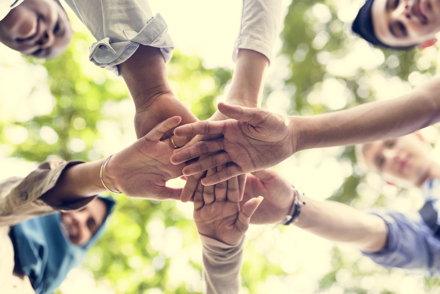 Diverse group joining hands — community programs and services